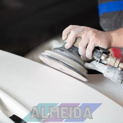 A man who sanding with a grinder and prepares the paint for the car in a car service. Repairman fix car paint.